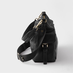 Black leather shoulder bag with gold-tone hardware, adjustable crossbody strap, and zip exterior pocket, shown from side angle