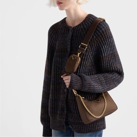 Model carrying chocolate brown shoulder bag with gold chain detail and crossbody strap, styled with dark ribbed knit cardigan