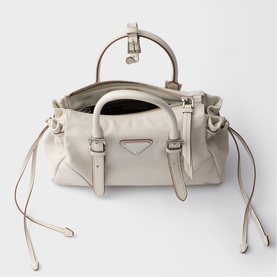 Prada ivory leather top-handle bag with silver-tone hardware, triangular logo plaque, buckle straps, and drawstring side ties