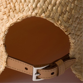 Prada Accessories neutral woven raffia bag, close-up of tan leather interior lining and silver-tone buckle strap detail.