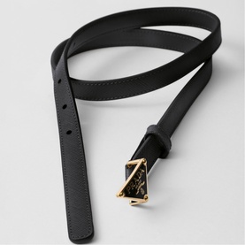 Black leather belt with decorative gold-toned buckle featuring ornate detailing, coiled on a light surface