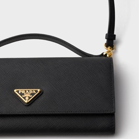 Prada black Saffiano leather mini bag with gold-tone triangular logo plaque and top handle, close-up detail shot