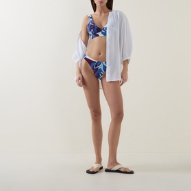 Model wearing Sea Level Denim Blue tropical print bikini bottom, styled with a white oversized shirt and black flip flops
