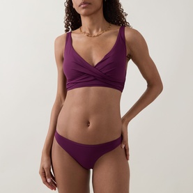 Model wearing Sea Level Essentials Cross Front Multifit Bikini Top in Claret with matching bikini briefs, twisted V-neckline detail visible