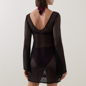 Model wearing Sea Level black crochet-style mesh cover-up, long sleeves, low scoop back, mini length, styled with burgundy neck scarf.