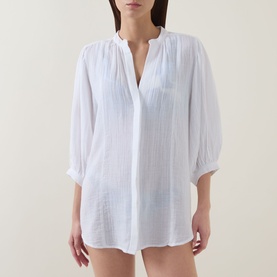 Model wearing Sea Level white cotton cover-up with V-neckline, button front, and cropped sleeves.