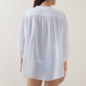 Model wearing Sea Level white cotton cover up, rear view, relaxed fit with gathered yoke and three-quarter sleeves