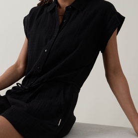 Model wearing Sea Level Sunset Textured Playsuit in black cheesecloth, featuring shirt collar, dropped shoulders, and elasticated drawstring waist