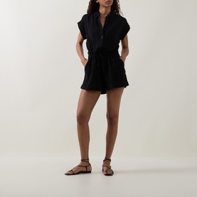 Model wearing Sea Level Sunset Textured Playsuit in black cheesecloth, shirt collar, drawstring waist, above-the-knee length, styled with tan flat