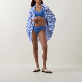 Model wearing Sea Level Vacay Striped Sarong in Chambray, styled with matching blue bikini set and white pearl necklace.