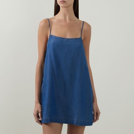 Model wearing Sea Level Denim Surf Mini Shift Dress in denim, featuring straight neckline, narrow adjustable straps and flared skirt silhouette