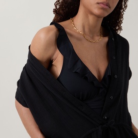 Model wearing Sea Level Essentials Edit Frill One-Piece Swimsuit in black, with V-neckline, soft frill detail, styled with a gold chain necklace.
