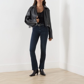 Model wearing Seven Jeans Tailorless Mid-Rise Bootcut Jeans in dark blue with black leather jacket, black top and black heeled ankle boots.