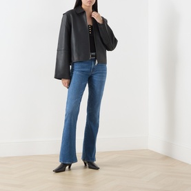 Model wearing Seven Jeans blue bootcut denim jeans, styled with a black leather jacket and black kitten heel boots.