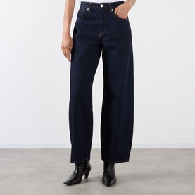 Model wearing dark indigo wide-leg jeans with high waist and cropped length, styled with black heeled ankle boots