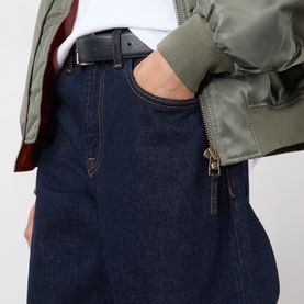 Model wearing dark indigo wide-leg jeans with zip detail, styled with olive bomber jacket and black leather belt