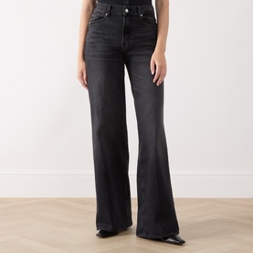 Model wearing Seven Jeans black wide leg jeans in washed denim, high-rise waist with classic five-pocket styling and flared hem.