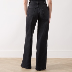 Model wearing Seven Jeans black wide leg jeans, rear view showing high waist, relaxed fit and raw hem detail.
