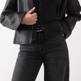 Model wearing Seven Jeans black wide leg jeans, styled with a black shirt, leather jacket and thin belt.
