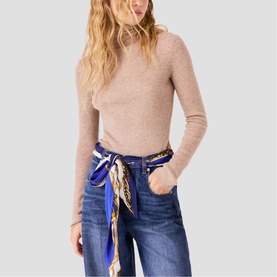 Model wearing Maje clear fine knit roll-neck jumper, styled with blue wide-leg jeans and a blue printed silk scarf tied at the waist
