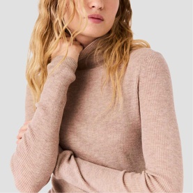 Model wearing Maje ribbed turtleneck jumper in clear beige, cropped close-up showing neckline and long sleeves