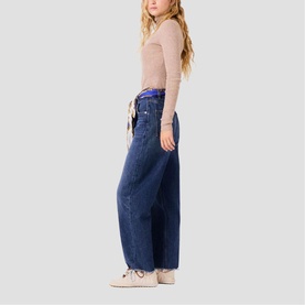 Model wearing Maje wide-leg dark blue jeans with drawstring waist, styled with a beige long-sleeve top and white trainers.