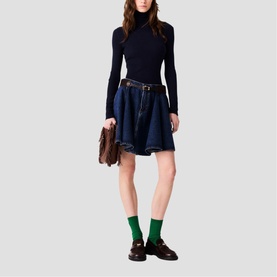 Model wearing Maje navy ribbed turtleneck and dark denim mini skirt with belt, styled with green socks, brown loafers, and small brown bag