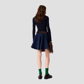 Model wearing Maje navy ribbed long-sleeve top and navy denim mini skirt, styled with green socks and black chunky loafers, carrying brown bag
