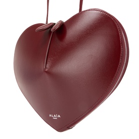 Alaia Le Coeur Crossbody Bag in Rouge Grenat, heart-shaped red leather with silver-tone logo lettering and zip-around fastening
