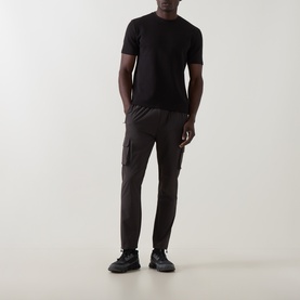 Model wearing Arne Utility Cargo Casual Trousers in grey, slim-leg with cargo pockets, styled with black T-shirt and black trainers