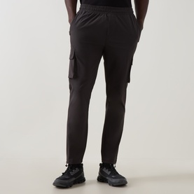 Model wearing Arne Utility Cargo Casual Trousers in grey, slim-leg fit with 3D cargo pockets and bungee cord hems, rear view