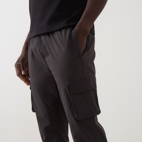 Model wearing Arne Utility Cargo Casual Trousers in grey, slim-leg fit with 3D cargo pocket detail, paired with a black T-shirt.