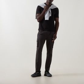 Model wearing Arne Utility Cargo Casual Trousers in grey with slim leg and cargo pockets, styled with black tee and trainers