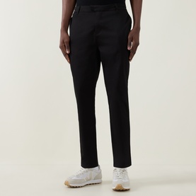 Model wearing Arne Tailored Slim-Leg Chinos in black, slim-leg fit with clean hems, styled with white trainers.