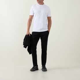 Model wearing Arne Essential Solid T-Shirt in white, crew neck, short sleeves, styled with black trousers and trainers, carrying a dark jacket.