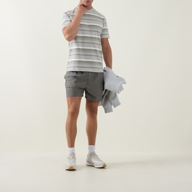 Model wearing Arne Marl Grey Crew Neck T-Shirt with striped pattern, styled with grey shorts and white trainers, holding a jacket.