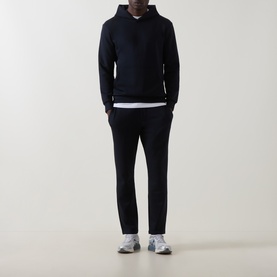 Model wearing Arne navy hoodie with matching navy trousers, white underlayer and grey trainers.