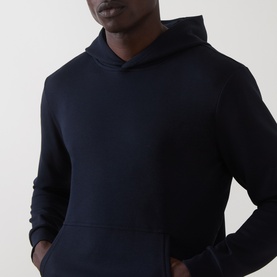 Model wearing Arne navy hoodie, close-up showing kangaroo pocket and ribbed hem detail