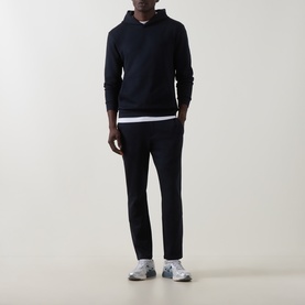 Model wearing Arne navy cotton-blend hoodie with white underlayer, styled with matching navy trousers and grey trainers.