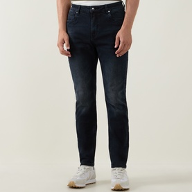 Model wearing Arne Slim-Leg Jeans in Midnight Blue, dark wash stretch denim, slim fit, styled with white trainers