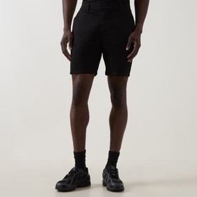 Model wearing Arne Tailored Slim-Leg Chino Shorts in black, mid-rise, knee-length, styled with black trainers and socks.