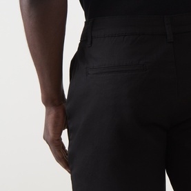 Model wearing Arne Tailored Slim-Leg Chino Shorts in black, close-up rear view showing jetted back pockets and slim fit.