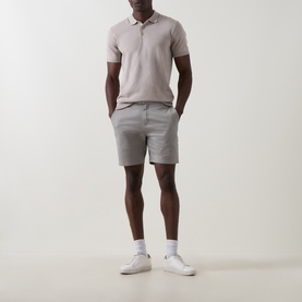 Model wearing Arne stone cotton shorts styled with a mauve polo shirt and white trainers.