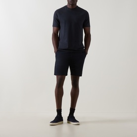 Model wearing Arne Tailored Slim-Leg Chino Shorts in navy, styled with a matching navy crew-neck tee and dark canvas shoes.