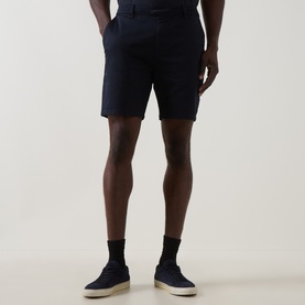 Model wearing Arne Tailored Slim-Leg Chino Shorts in navy, styled with black socks and navy canvas trainers