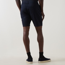 Model wearing Arne Tailored Slim-Leg Chino Shorts in navy, rear view, styled with black socks and navy canvas shoes