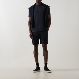 Model wearing Arne Tailored Slim-Leg Chino Shorts in navy, styled with a matching navy tee, gilet, and dark slip-on shoes.