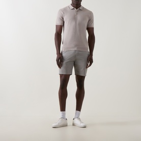 Model wearing Arne Stone knit polo shirt, styled with grey shorts and white trainers
