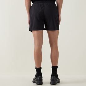 Model wearing Arne Essential Drawstring Swim Shorts in black, rear view, styled with black trainers and ankle socks.