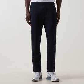 Model wearing Arne navy sweatpants in cotton-polyester blend, styled with white trainers, straight-leg relaxed fit.